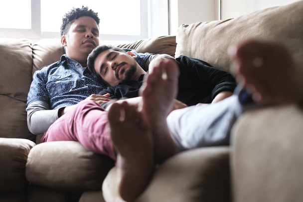 Νέοι ομοφυλόφιλοι άνδρες στον ύπνο και να χαλαρώσετε στον καναπέ στο σπίτι - Φωτογραφία, εικόνα