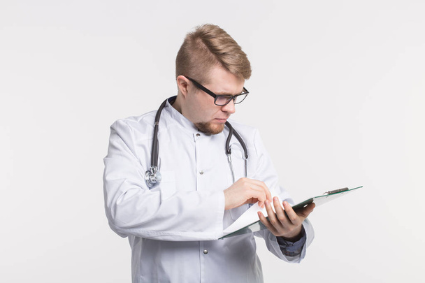 Medizin und Gesundheitskonzept - lächelnder Arzt mit Stethoskop-Aktenmappe auf weißem Hintergrund - Foto, Bild