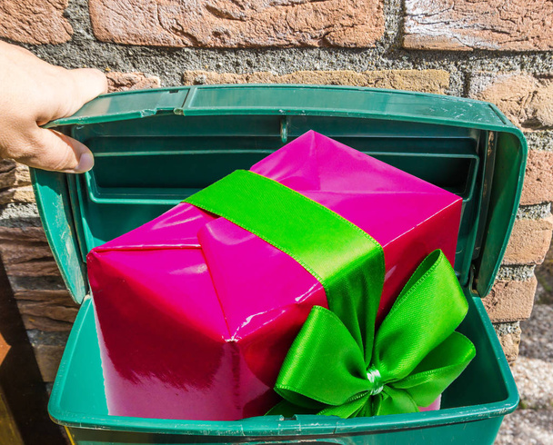 Великий рожевий різдвяний подарунок зі стрічкою в класичній зеленій поштовій скриньці
 - Фото, зображення