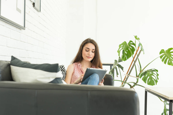 Technologii, komunikacji, ludzie koncepcja - młoda kobieta siedzi na skórzanej kanapie i za pomocą cyfrowego tabletu - Zdjęcie, obraz