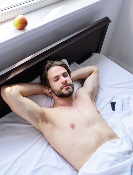 Guy sexy macho lay white bedclothes. Man sleepy drowsy unshaven bearded face having rest. Pleasant relax concept. Let your body feel comfortable. Man unshaven handsome guy naked torso relaxing bed - 写真・画像
