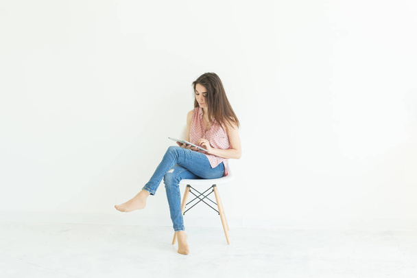 pessoas, tecnologia e conceito de educação - jovem estudante mulher sentada em uma cadeira e usando um tablet em fundo branco com espaço de cópia
 - Foto, Imagem