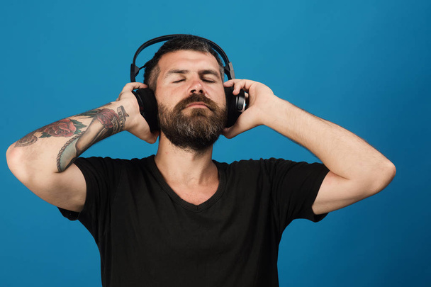 Man holds headphones on blue background. Pleasure, music and lifestyle - Valokuva, kuva
