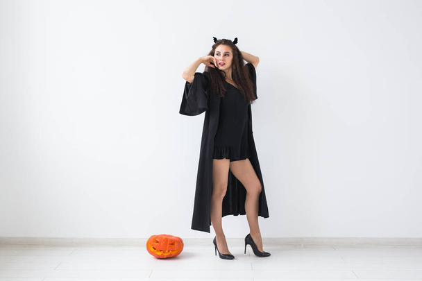 Muotokuva tyylikäs brunette nainen halloween kurpitsa yli kevyt tausta kopioi tilaa
 - Valokuva, kuva