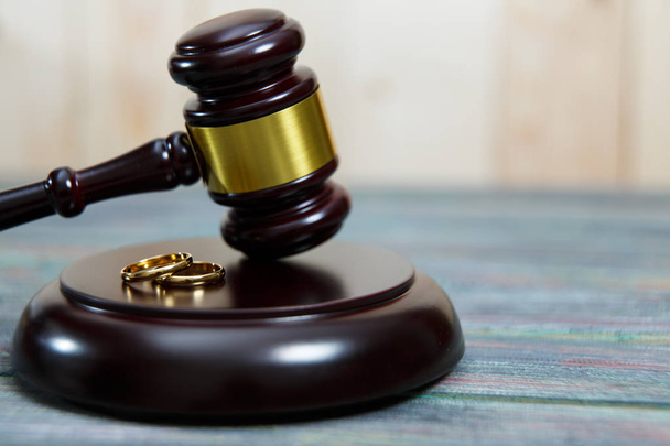Closeup de anéis de casamento em martelo de madeira à mesa
 - Foto, Imagem