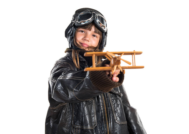 Giovane ragazza con cappello da pilota in possesso di un aeroplano giocattolo in legno
 - Foto, immagini