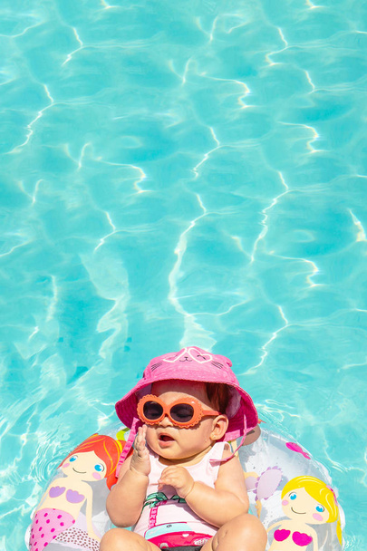 Beautiful Baby Girl Wearing Hat and Sunglasses On A Float In Clear Water - Photo, image