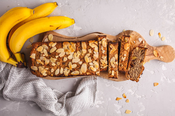 Homemade vegan banana bread with almonds and chocolate, gray background. Clean eating concept. - 写真・画像