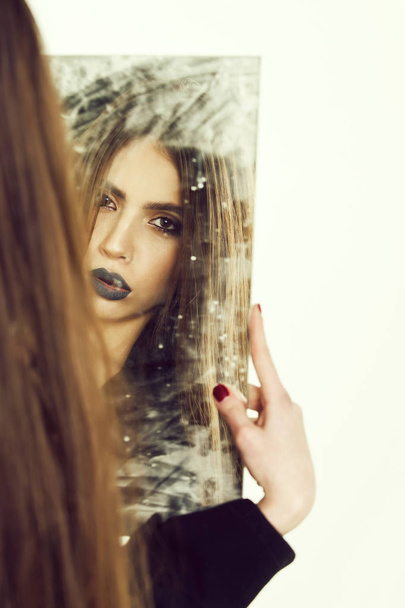 sensual young lady looking, holding dirty mirror with black lipstick - 写真・画像