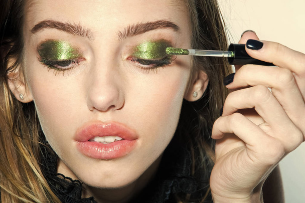 Girl put eyeshadow on eyes with brush, new technology. - Foto, Imagen