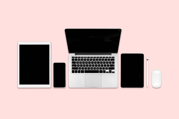 ラップトップ コンピューター、デジタル タブレット、携帯電話、アクセサリーとのオフィスのテーブルのフラット レイアウトの写真。ピンクのトーンは現代の背景。デスクトップ オフィス モックアップ コンセプト. - 写真・画像