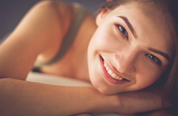 Closeup of a smiling young woman lying on couch - Photo, image
