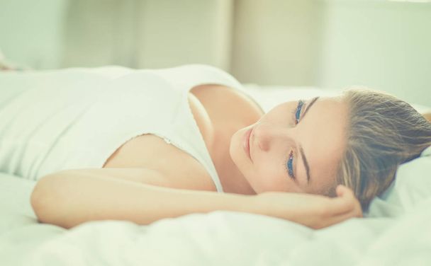 Gyönyörű fiatal nő fekszik az ágyban kényelmesen és boldogan - Fotó, kép