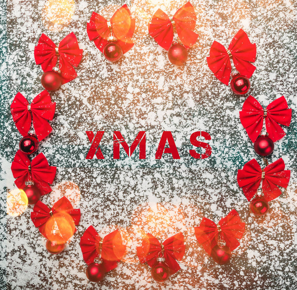 Rode kerstballen met lint bogen en xmas label op winter witte achtergrond. Bovenaanzicht, bokeh effect - Foto, afbeelding