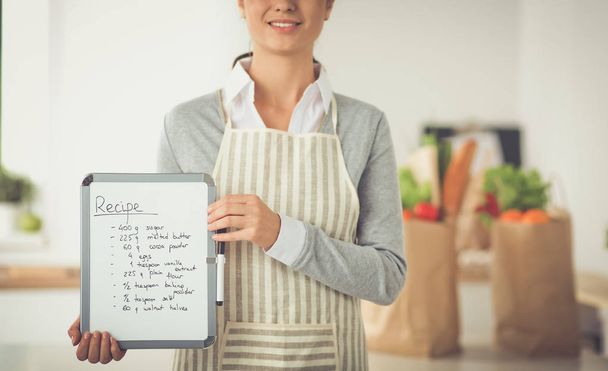 Woman in the kitchen at home, standing near desk with folder - Photo, image