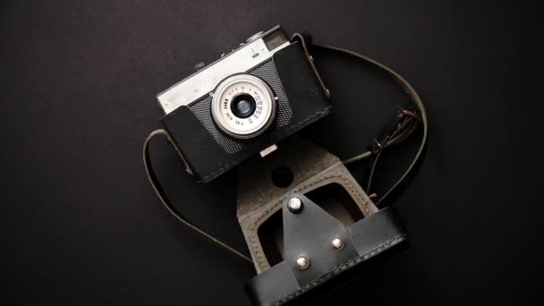 Old retro film camera in leather case on black background - Footage, Video