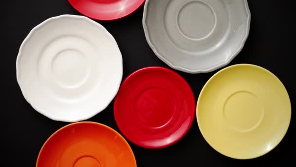 Colorful empty plates and saucers over black background. - Footage, Video