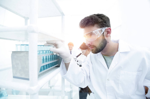 Een jonge man bezig met een experiment in een chemisch laboratorium - Foto, afbeelding