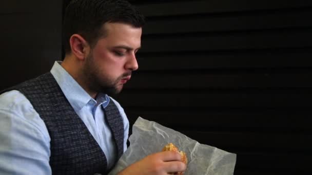 portret Brodaty mężczyzna jedzenie kanapka z bliska. Materiały wideo full hd w czasie rzeczywistym. Fast food. Widok z boku - Materiał filmowy, wideo