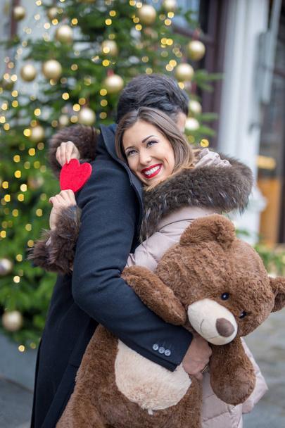 Счастливая молодая пара обнимается и обменивается подарками на Рождество.
 - Фото, изображение