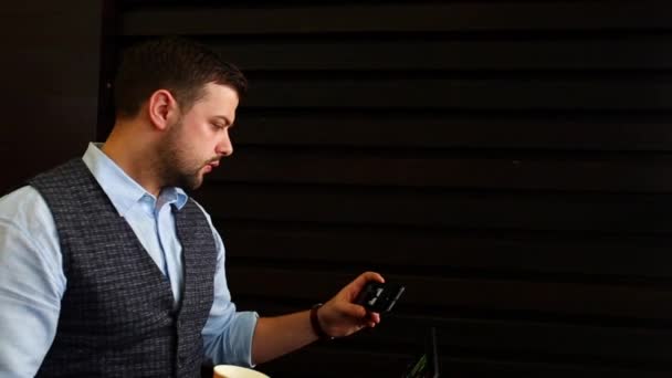 freelancer hombre de negocios que trabaja en el ordenador portátil con diagramas en la pantalla en la cafetería, comprobar la aplicación de teléfonos inteligentes para obtener información y actualizaciones y beber café. Seguimiento y disparo revelador
 - Imágenes, Vídeo