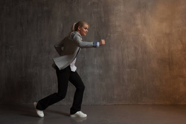 Young woman in business suit and sneakers. runner's pose, ready to run a long distance - Foto, Bild