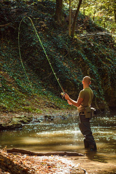 Un pescatore pesca con la pesca a mosca nel torrente che scorre
 - Foto, immagini