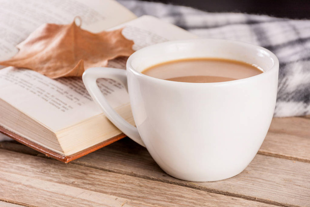 Кофейная чашка на ретро деревянный стол и открытая книга с упал сухой лист и одеяло размыты в фоновом режиме. Осенний концепт изображения. Крупный план, избирательный фокус
 - Фото, изображение