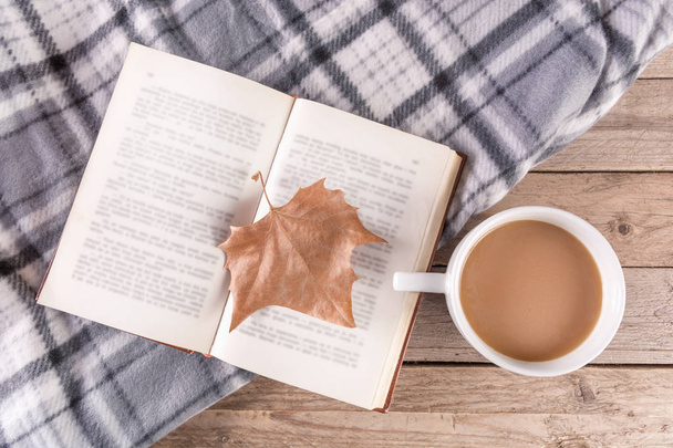 Kuru düşmüş yaprak ve kahve ile açık bir kitap üzerinde ahşap arka plan ve retro battaniye. Sonbahar konsepti görüntü. Üstten görünüm, seçici odak - Fotoğraf, Görsel
