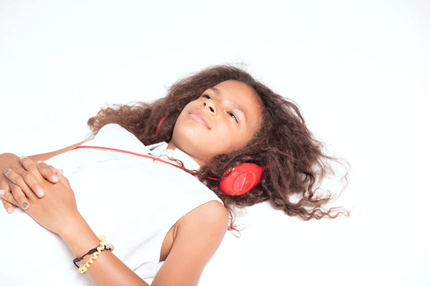 Young african american girl listening music with headphones, relaxing, lying on the floor. - Fotografie, Obrázek