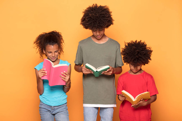 Happy smiling three afro children in colorful clothes posing together, reading books. - Fotoğraf, Görsel