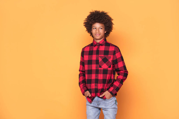 African american teenager in fashionable shirt. Studio shot. Young boy posing on yellow background. - Photo, Image