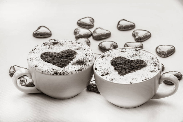 zwei Tassen Kaffee mit Herz-Symbol und Süßigkeiten herum. Bild im Schwarz-Weiß-Farbstil - Foto, Bild