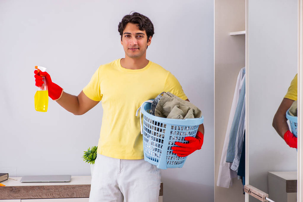 Fiatal jóképű férfi takarítás a hálószobában - Fotó, kép