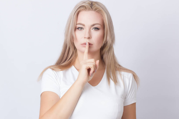 Postrait of confident woman with long blonde hair doing stop gesture with hand over grey background - Photo, image