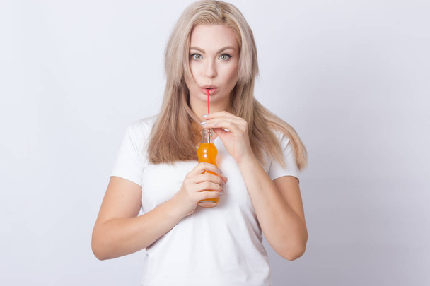 Studio photo portrait of cute blonde woman with bottle with soda in her hands. Over grey background - Фото, зображення