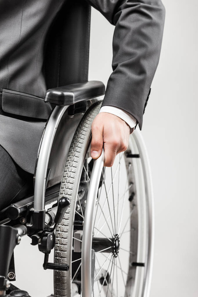 Business career and professional competition success concept - invalid or disabled businessman in black suit sitting wheelchair white isolated - Фото, зображення