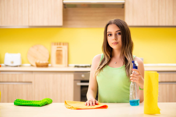 Jonge mooie vrouw polijsten tafel in de keuken  - Foto, afbeelding
