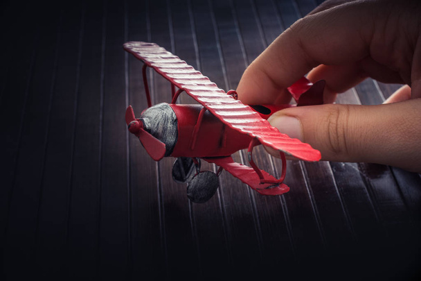 Hand holding a red toy plane on a on wooden texture - Photo, Image