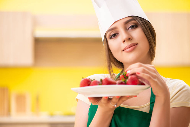 Young female cook eating strawberries - 写真・画像
