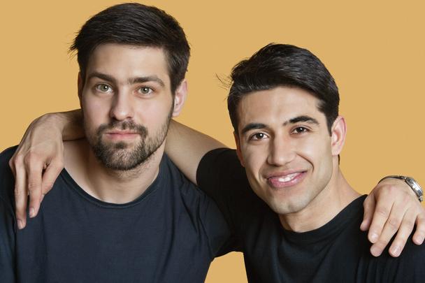 Portrait of a young male friends with arms around over colored background - Foto, afbeelding