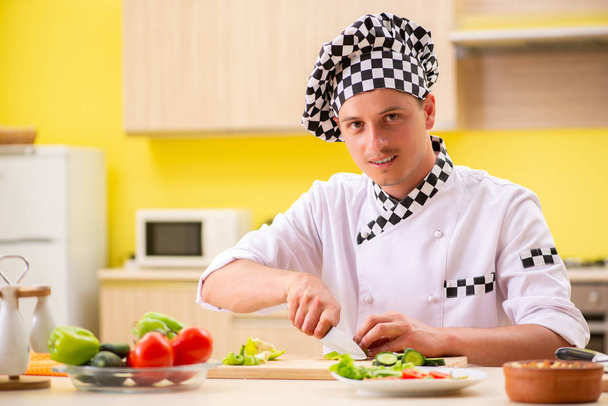 Joven cocinero profesional preparando ensalada en la cocina - Foto, Imagen