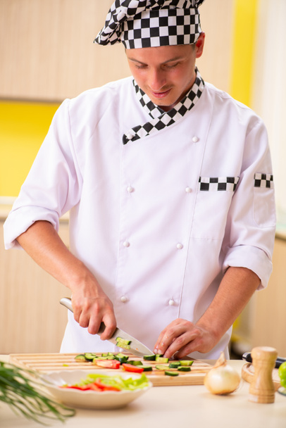Jeune cuisinier professionnel préparant la salade à la cuisine - Photo, image