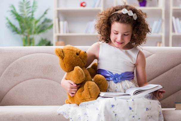 Маленькая симпатичная девочка читает дома книги - Фото, изображение