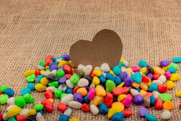 Paper heart amid colorful pebbles on canvas ground - Photo, Image