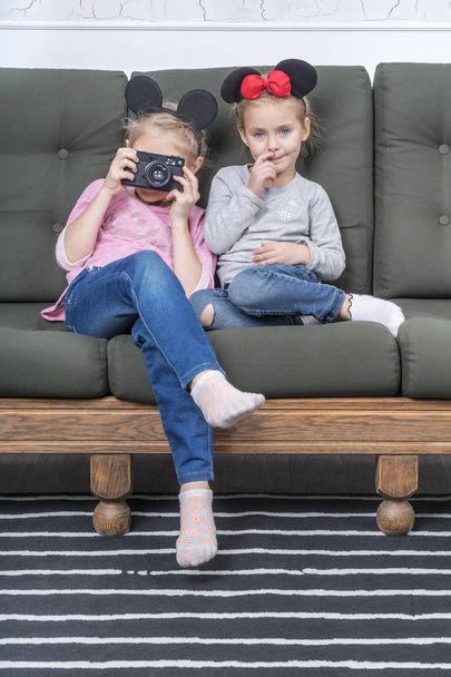 Two sisters dressed as a mouse sitting on the couch and photographed with a retro camera - Fotoğraf, Görsel
