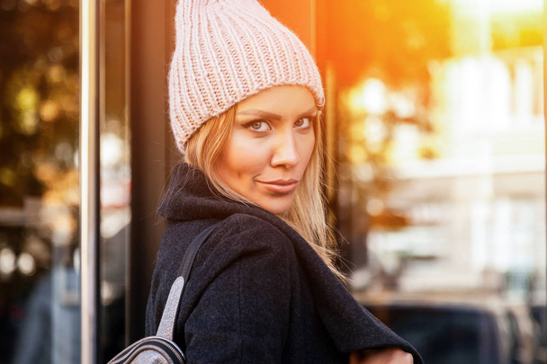 Portrait étudiante sur fond lumineux. Belle jeune femme urbaine moderne portant un chapeau de tricot rose sourire, regarder l'appareil photo et engoy journée ensoleillée d'automne
.  - Photo, image