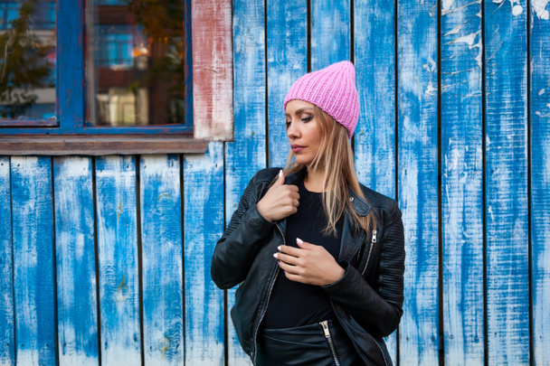 Portret vrouwelijke student op lichte achtergrond. Mooie moderne stedelijke jonge vrouw die het dragen van roze breien hoed glimlach, kijk weg en engoy zonnige herfstdag.  - Foto, afbeelding