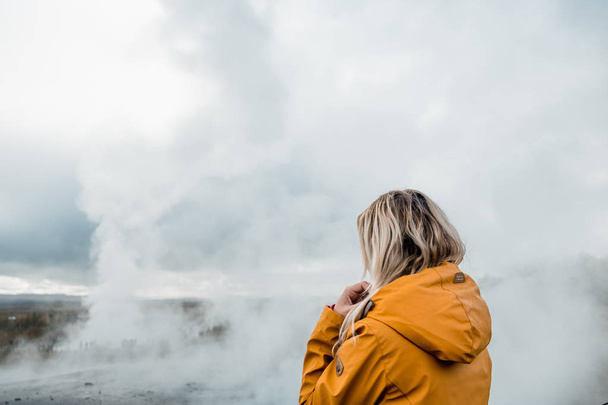 женщина в жёлтой куртке смотрит на туманный скандинавский пейзаж, Исландия
 - Фото, изображение
