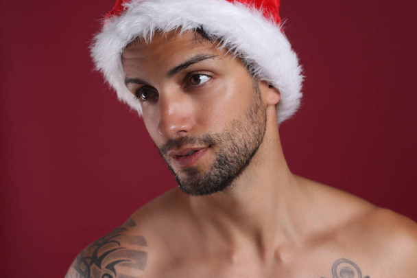 Sexy man in santa hat on red background  - Photo, Image